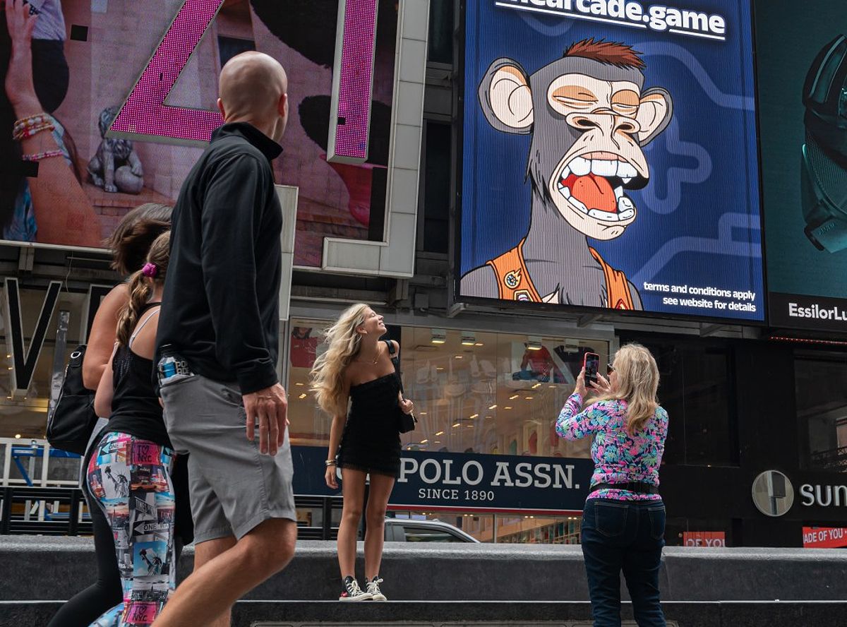 People take photos by a Bored Ape Yacht Club NFT billboard in Times Square in June 2022.